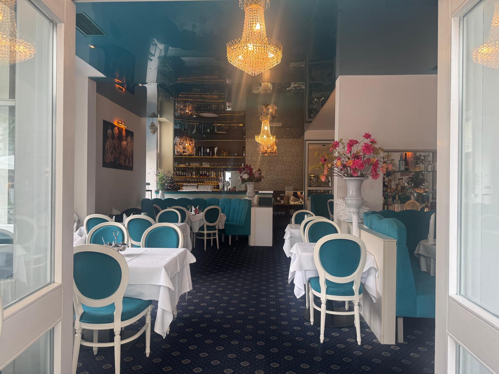 Eleganter Gastraum im Taj Tandoori mit Kronleuchtern und türkisen Samtstühlen